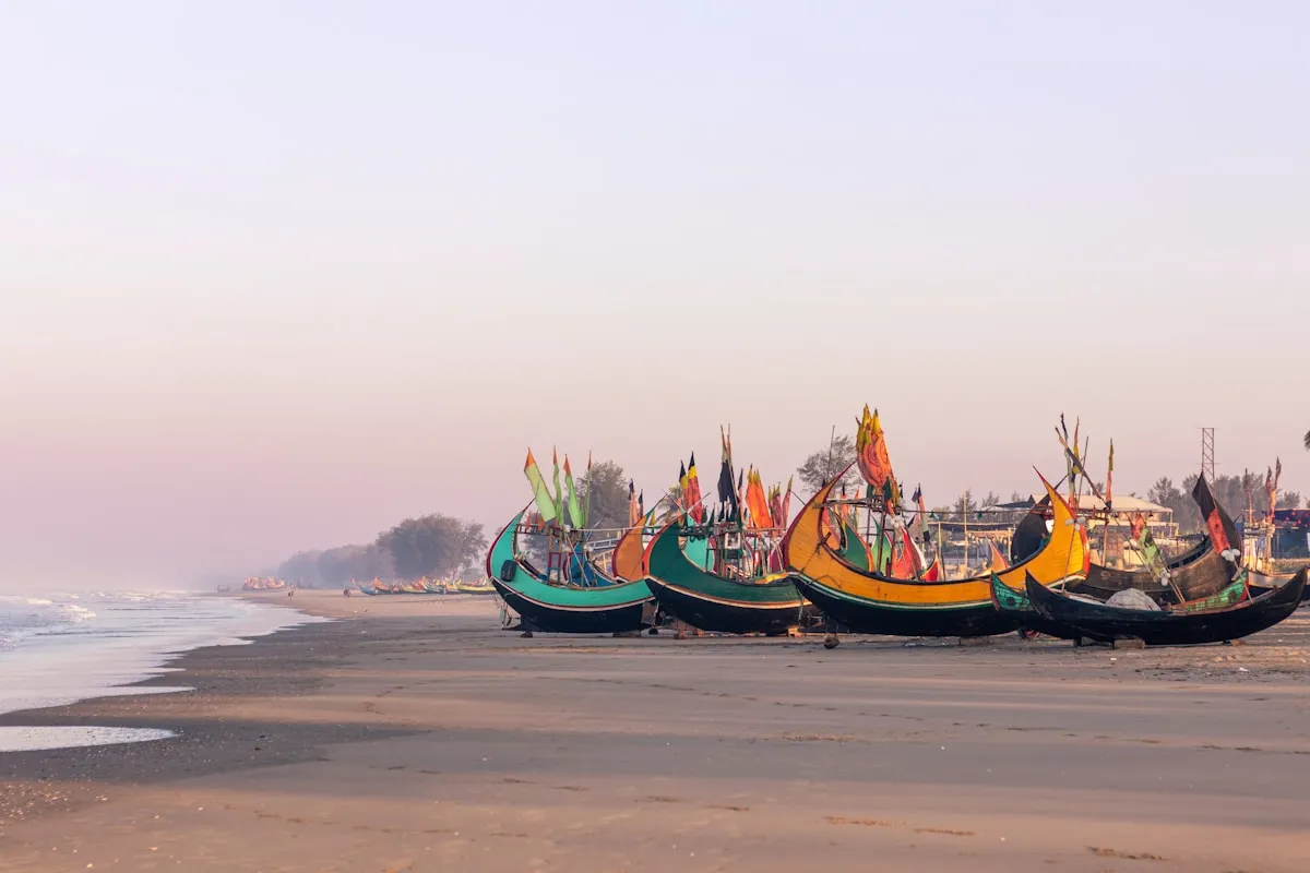 Colourful wooden fishing boats moored on the sandy shore at Cox's Bazar