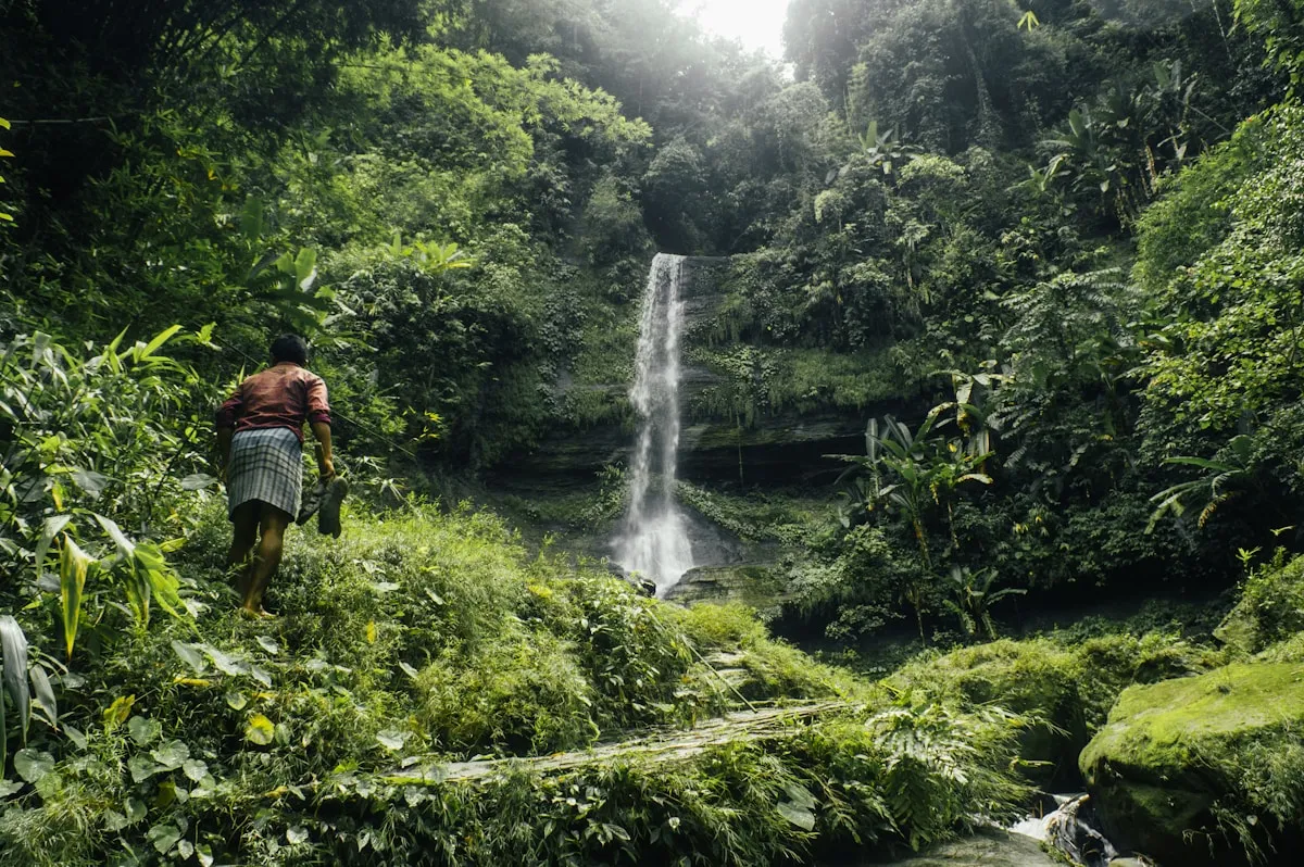 A waterfall cascading through lush forested hills in the Chittagong Hill Tracts