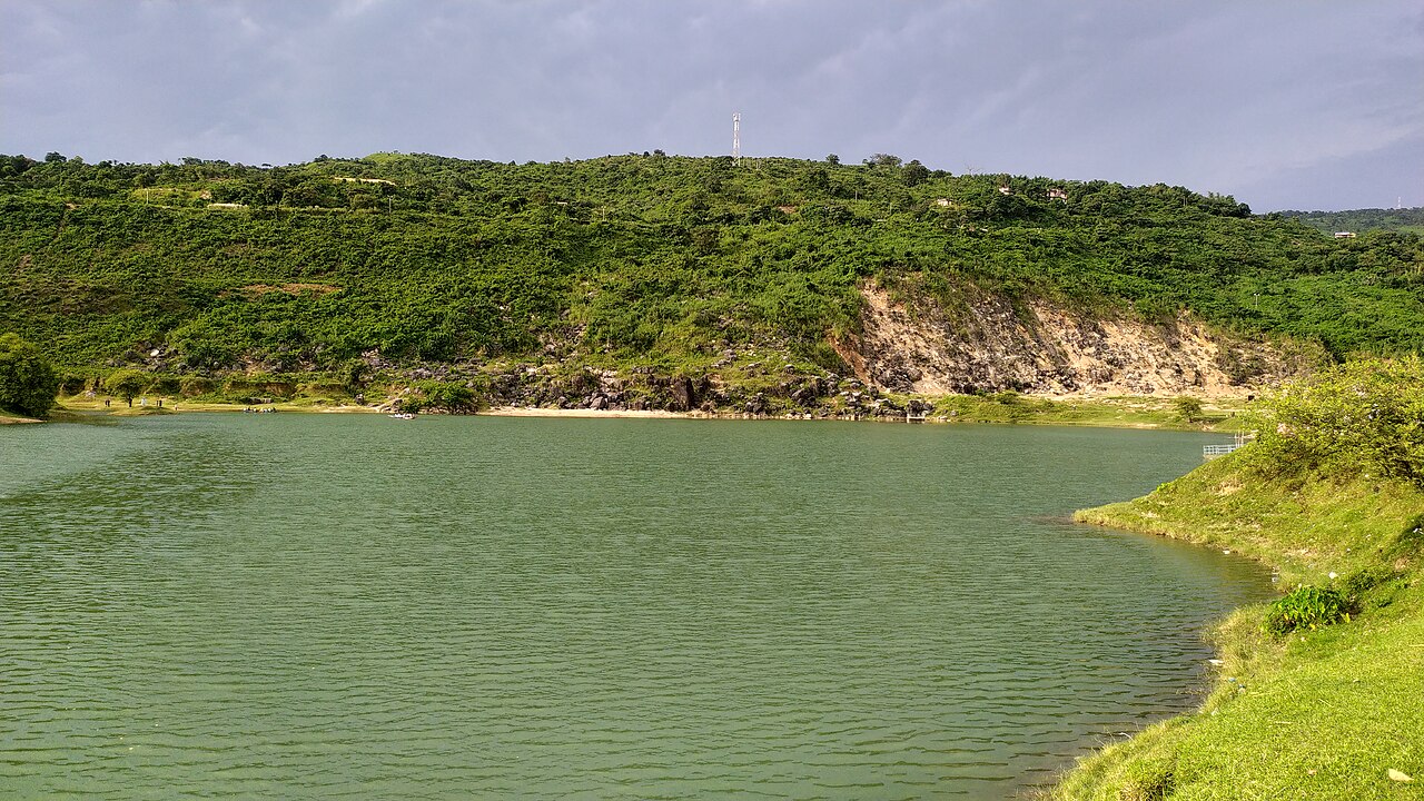 Turquoise water of Niladri Lake against a green quarry hillside, Sunamganj, Bangladesh