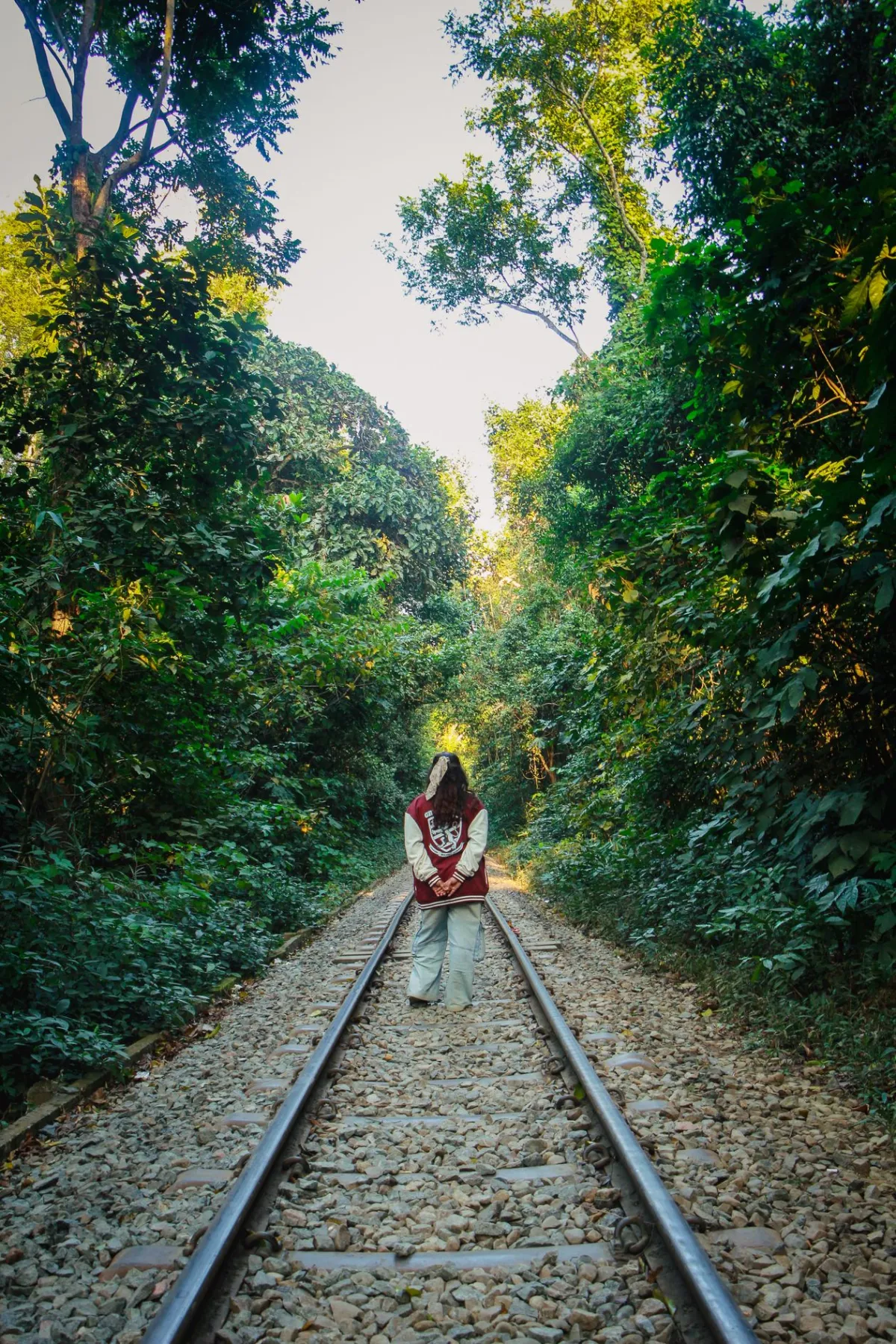 A woman walking along a jungle railway track in Sylhet